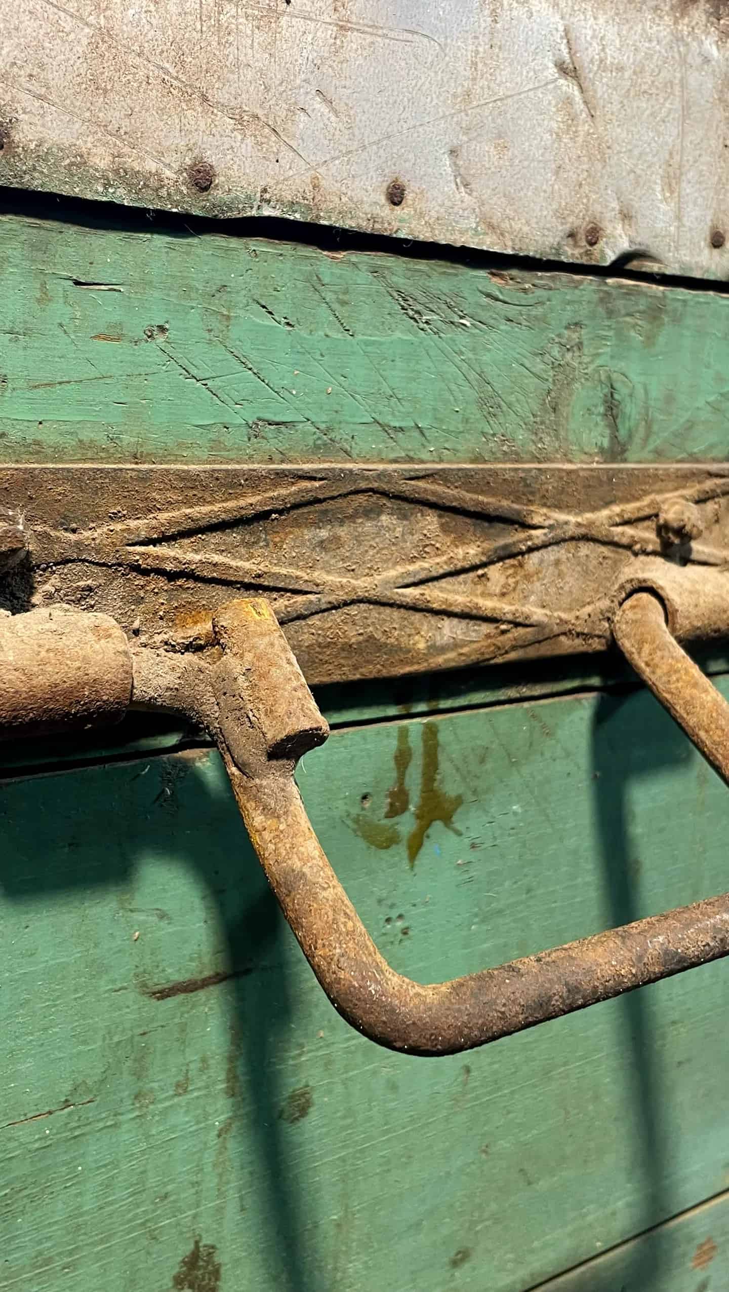 Detalle de asa de hierro oxidado sobre madera verde envejecida