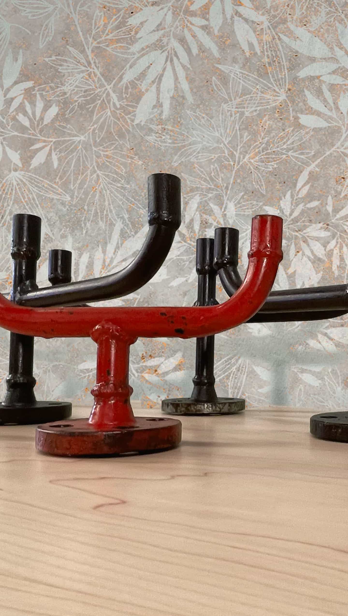 Detalle de candelabros de hierro en rojo y negro sobre superficie de madera