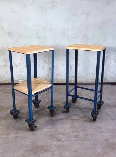 Dos carritos auxiliares industriales azules con ruedas y tablero de madera