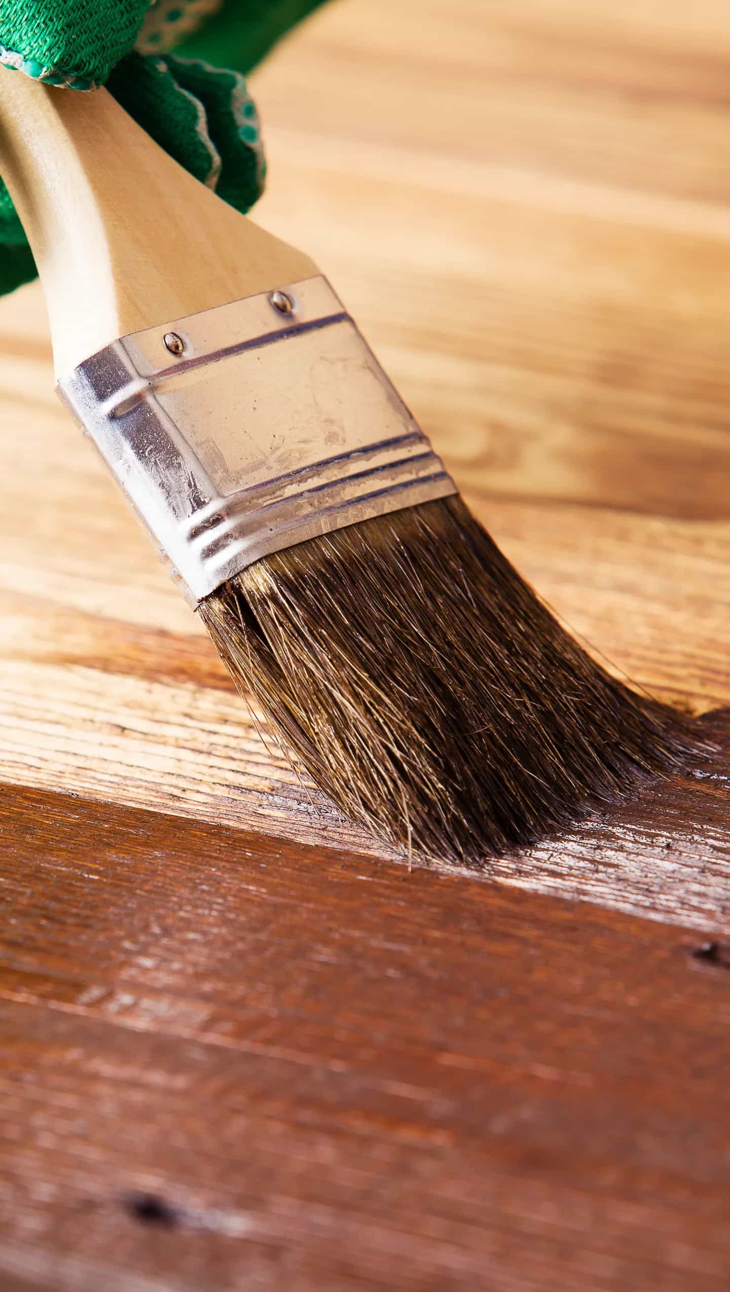 Pincel aplicando barniz sobre madera en proceso de restauración